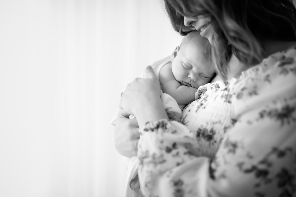 Black & white image of mother holding newborn baby close
