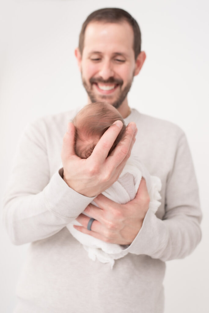 Smiling dad cradling newborn baby.