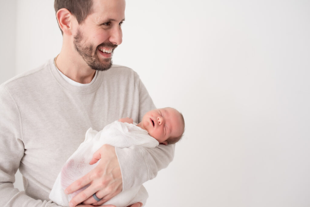 Smiling dad with newborn baby